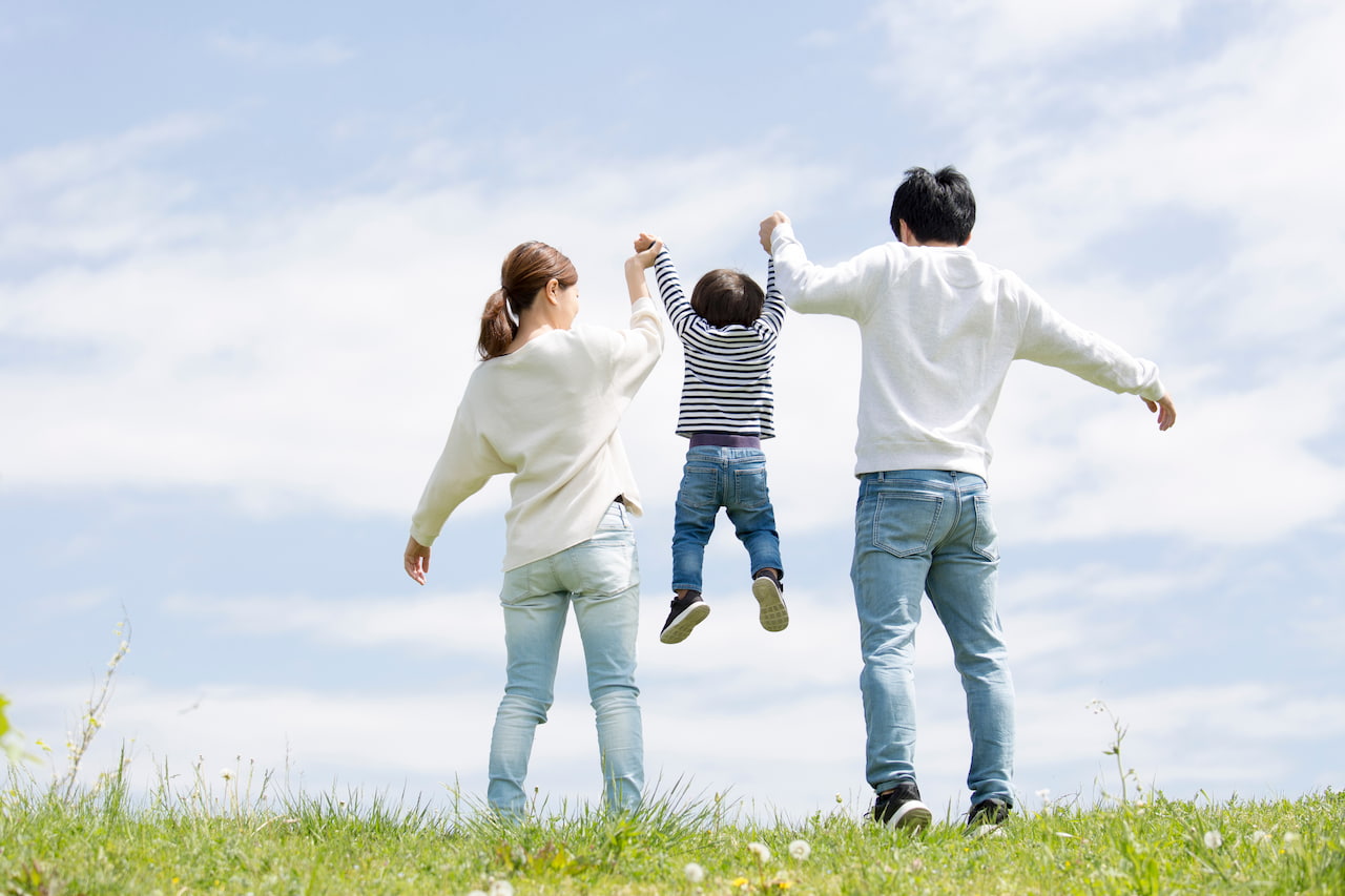 草原で遊ぶ家族の後ろ姿