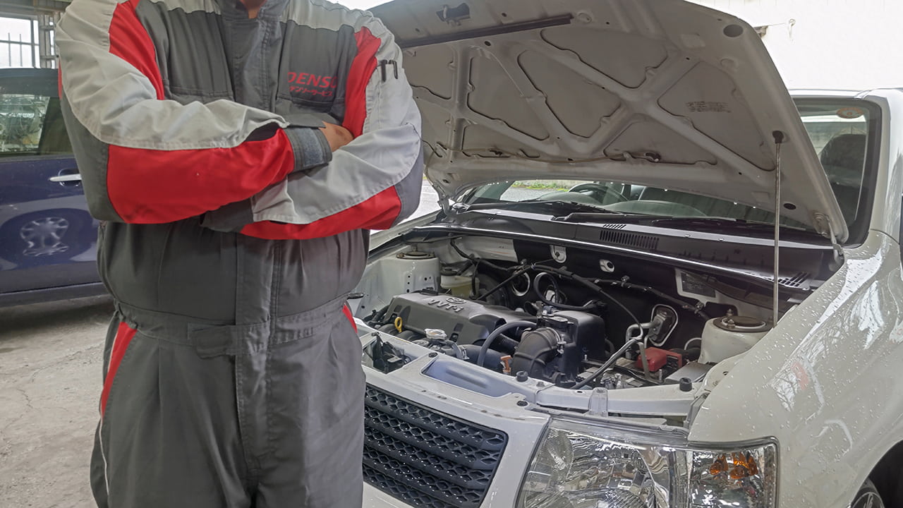 車の前で腕を組む自動車整備士